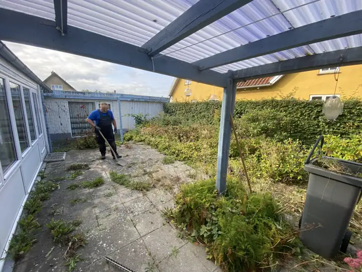 Havemand i gang med oprydning under en carport